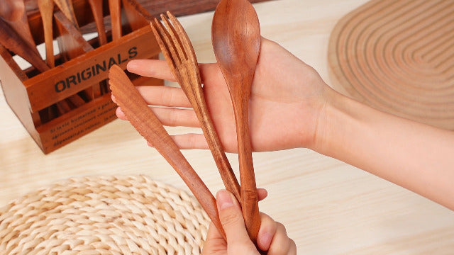 Set of 12 wooden serving utensils including spoons, forks, and knives made from walnut wood by Geiserailie.
