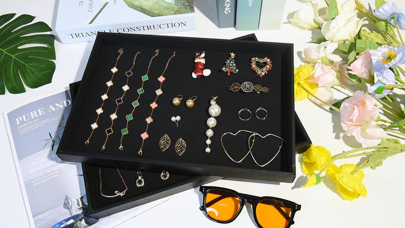 Two black velvet stackable jewelry trays with compartments for necklaces, bracelets, and rings, ideal for organized jewelry display.